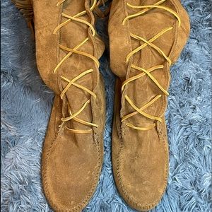 MINNETONKA Calf high lace up tan moccasin w/ tassel trim across top.
